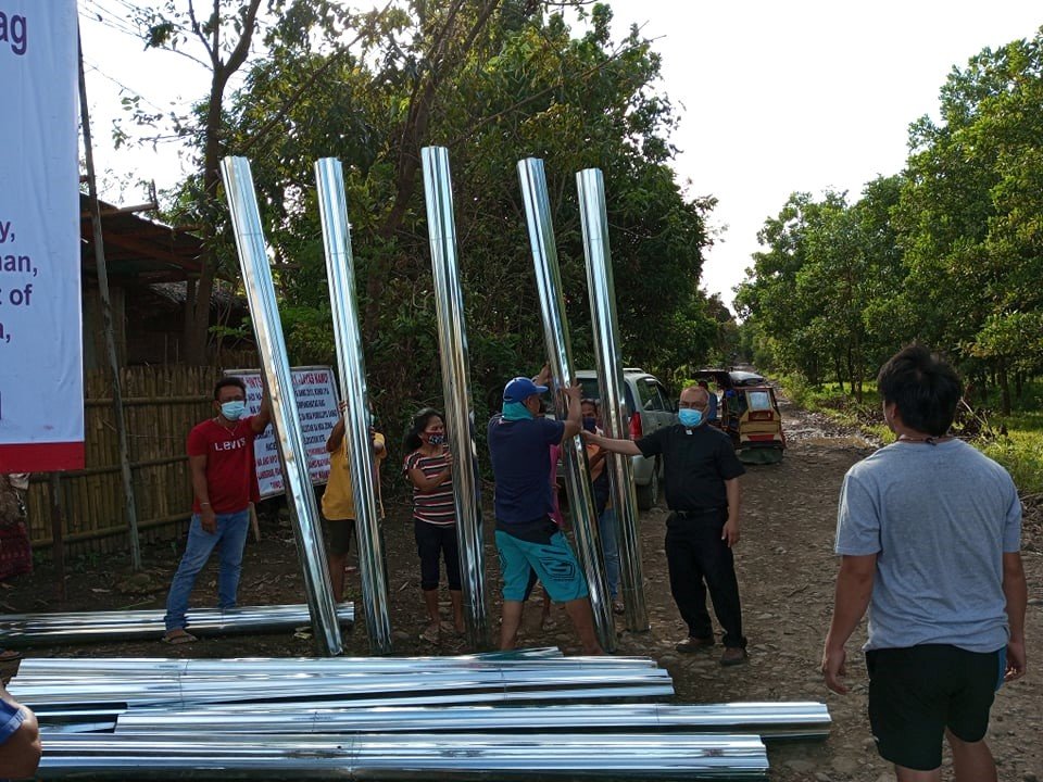 Father Donardo “Dandi” Bermejo and his coworkers distribute sheets of galvanized metal for people to repair their roofs that were damaged in the storm.